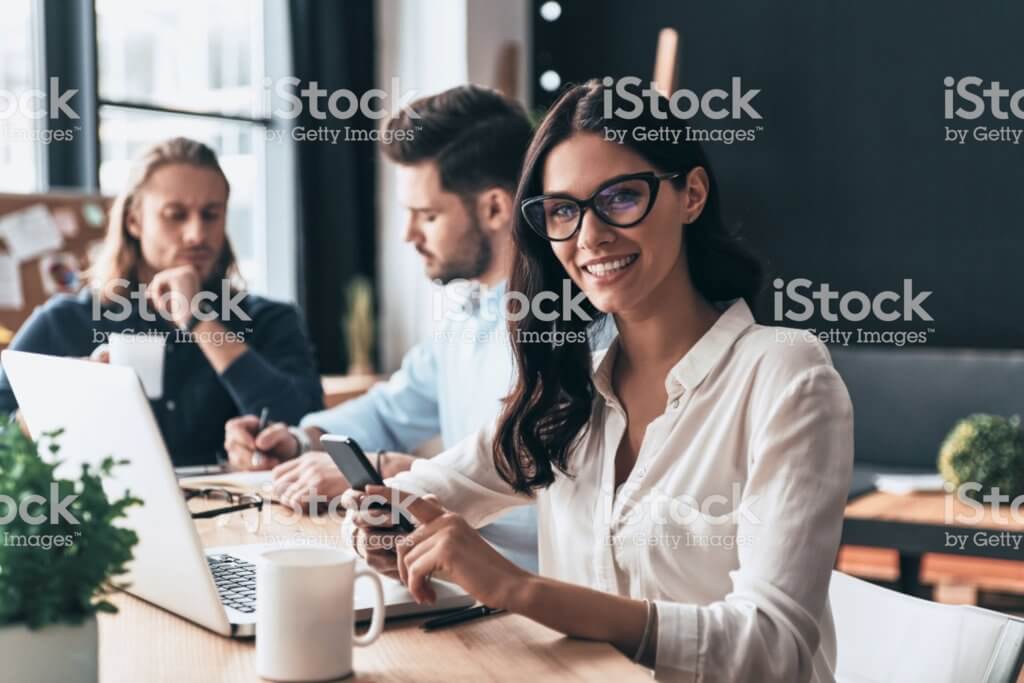 Young modern colleagues in smart casual wear working while spending time in the office