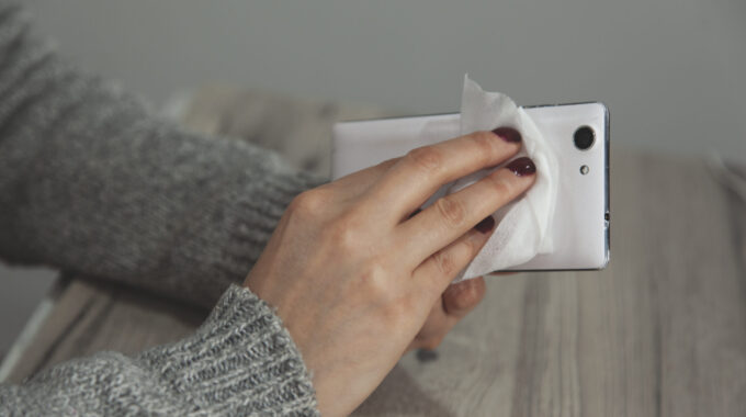 The Woman Cleans The Cell Phone With A Napkin