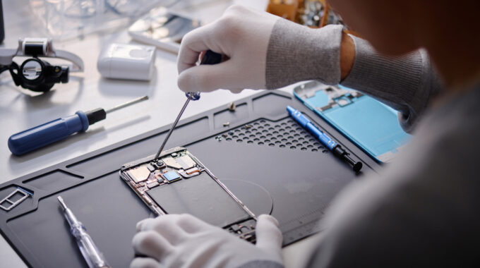 Over Shoulder Shot Of Unrecognizable Technician Repairing Disassembled Smartphone With Screwdriver