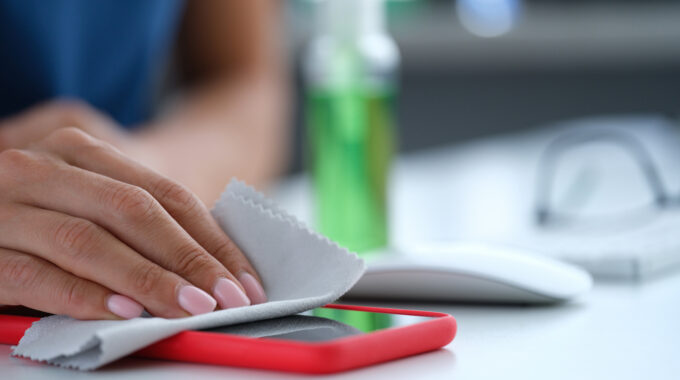 Woman Hand Wiping Screen Of Mobile Phone With Antiseptic Napkin Closeup. Prevention Of Coronavirus Infection During Covid19 Pandemic Concept