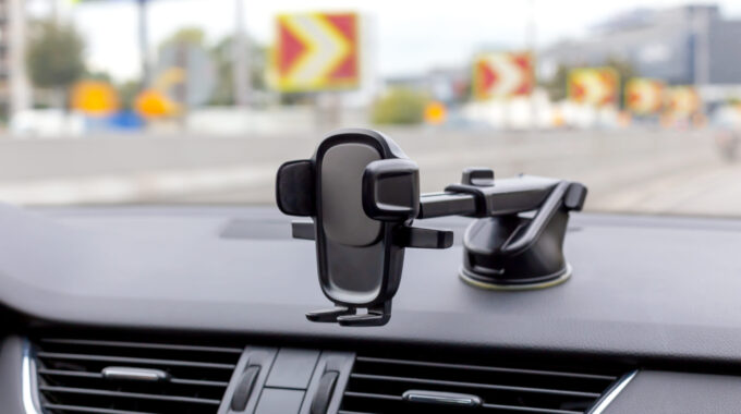 Phone Holder On The Car Dashboard. Blurred View Of Traffic Through The Windshield